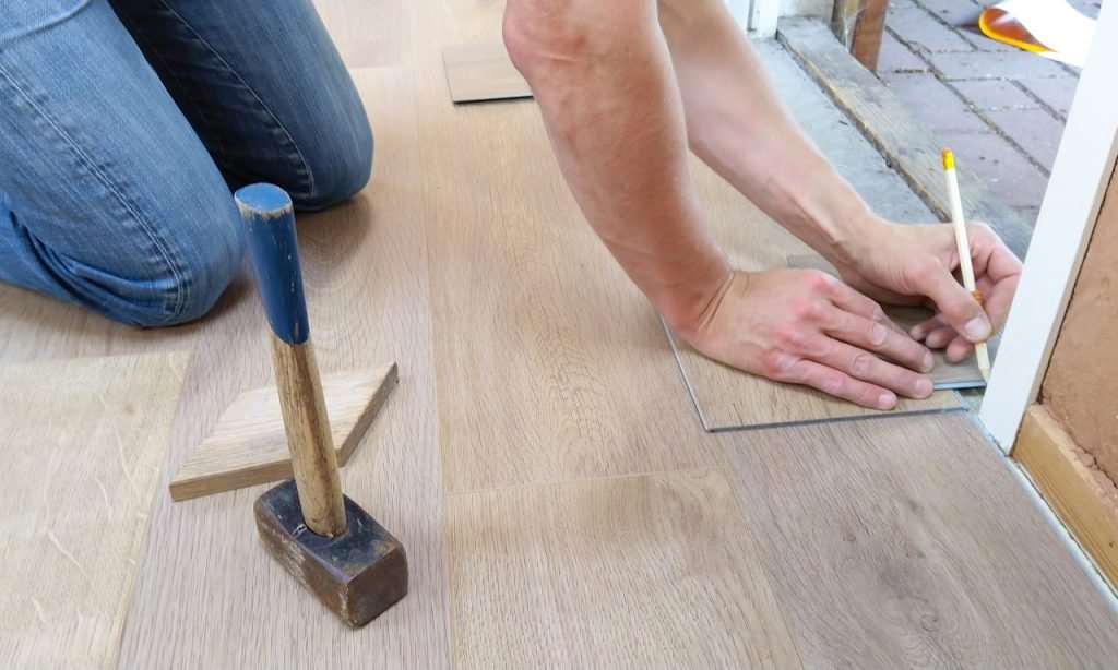 person-holding-pencil-1388944 A craftsman carefully measures and marks wooden floor panels for precise installation.